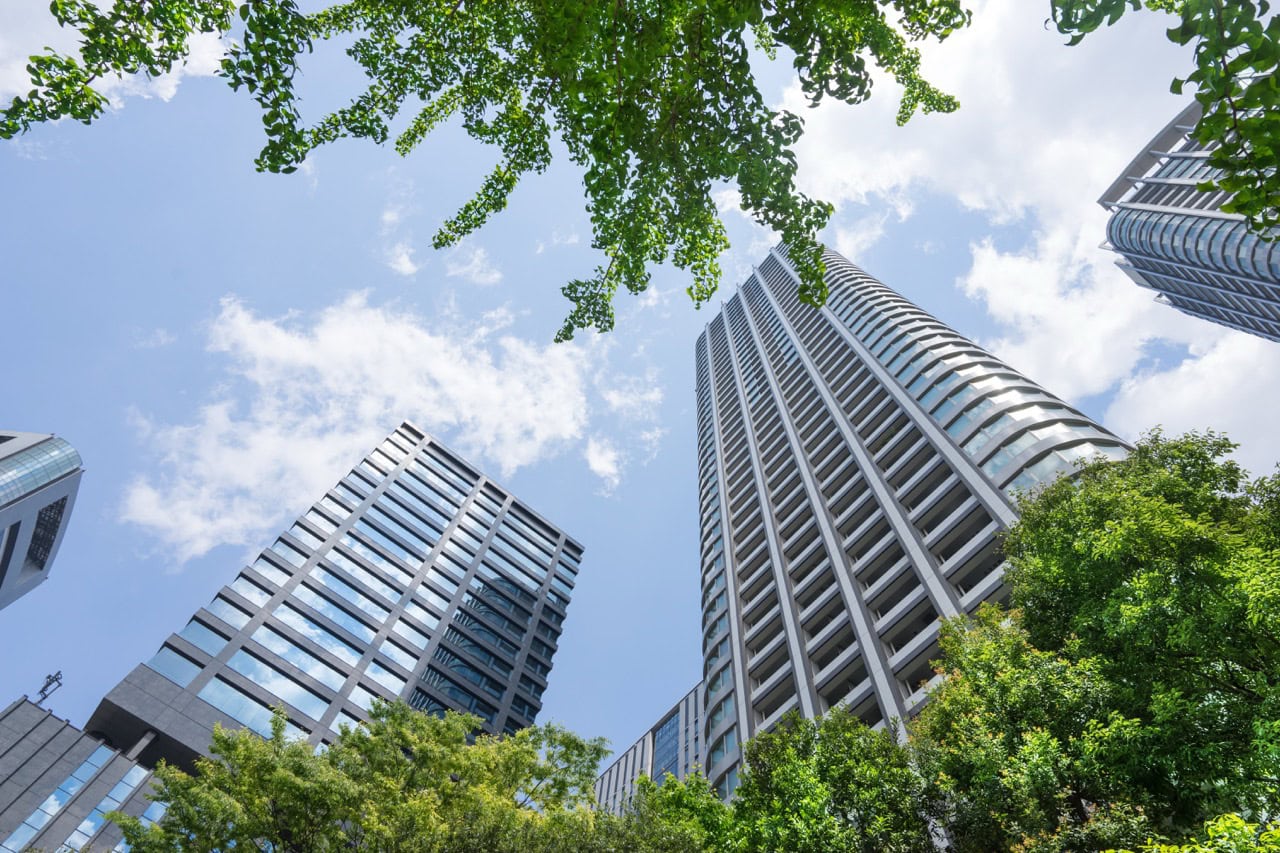 Modern condominium skyscrapers in Toronto with lush greenery and bright blue sky.