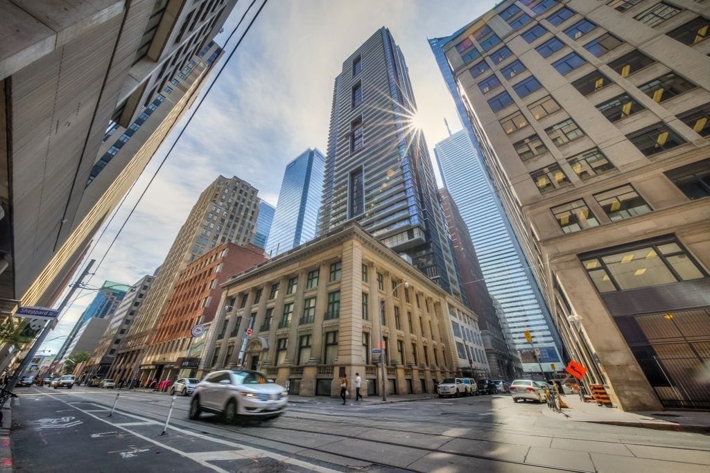 Modern Toronto buildings with sunlight glare and busy streets, highlighting urban development.